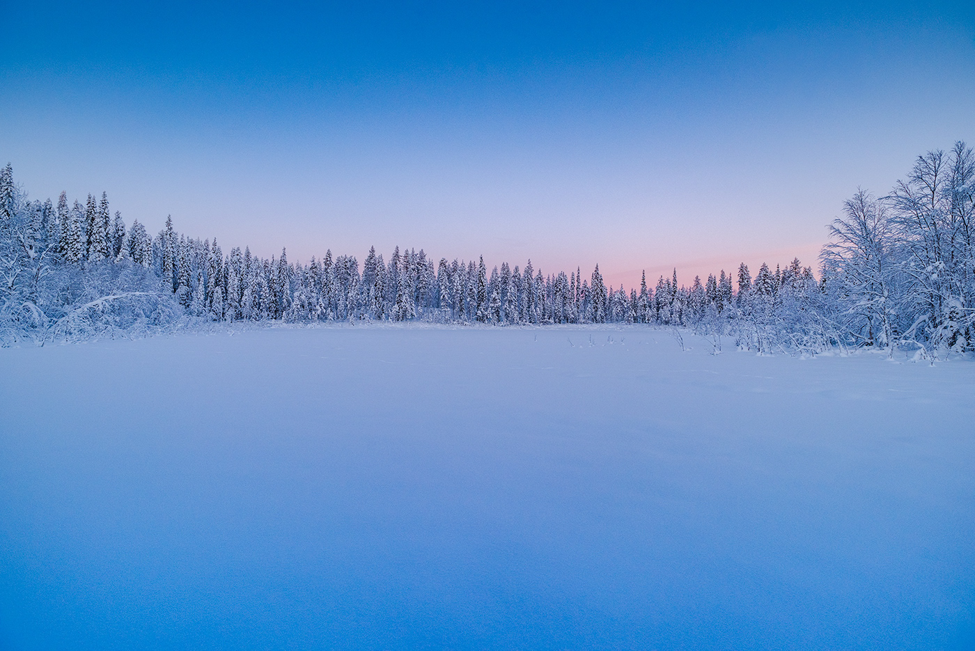 Frozen lake in northern Sweden at sunrise photographed by Jennifer Esseiva.