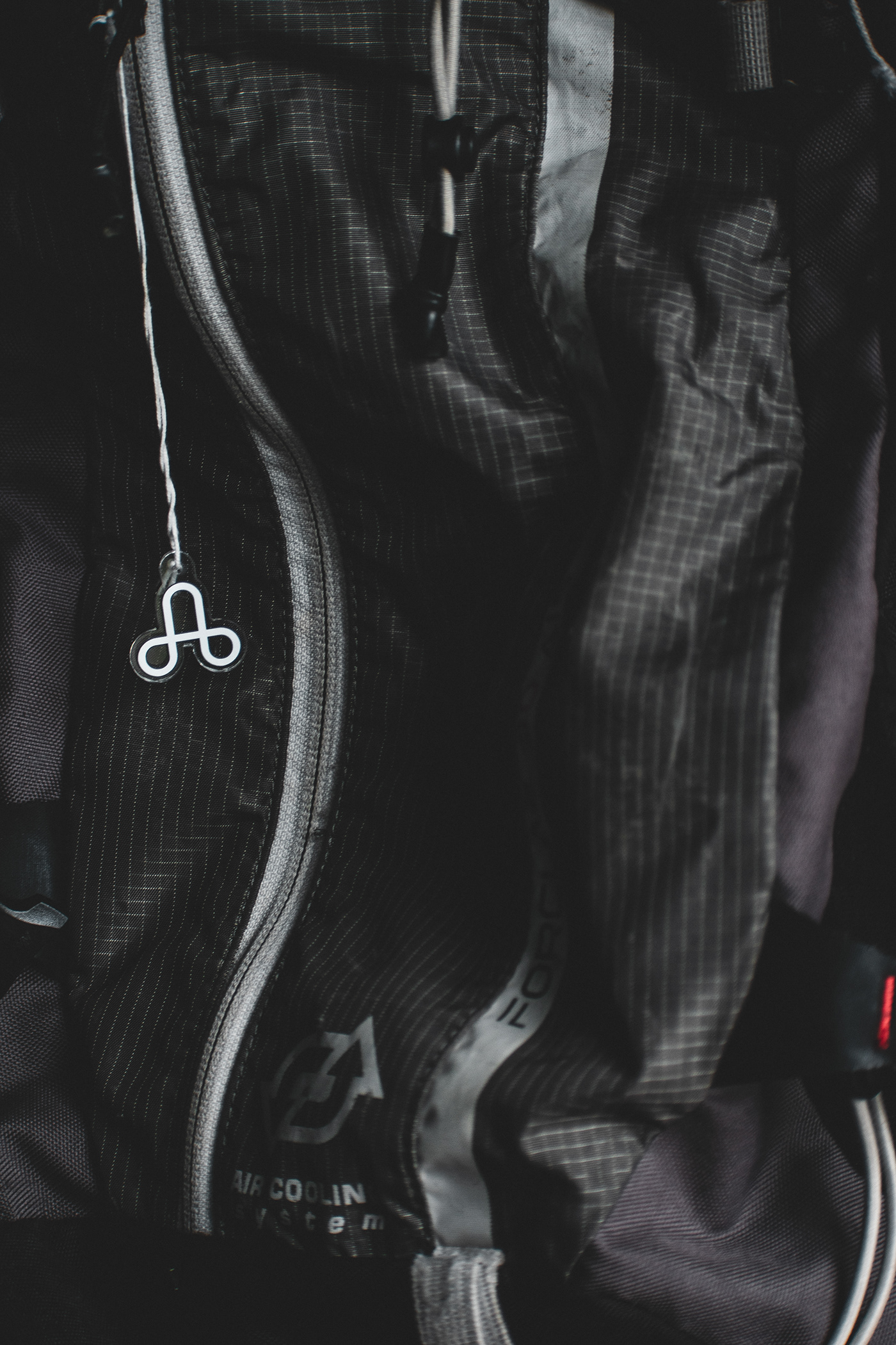 A vertical photograph of the icon for The Uprising hanging on a backpack