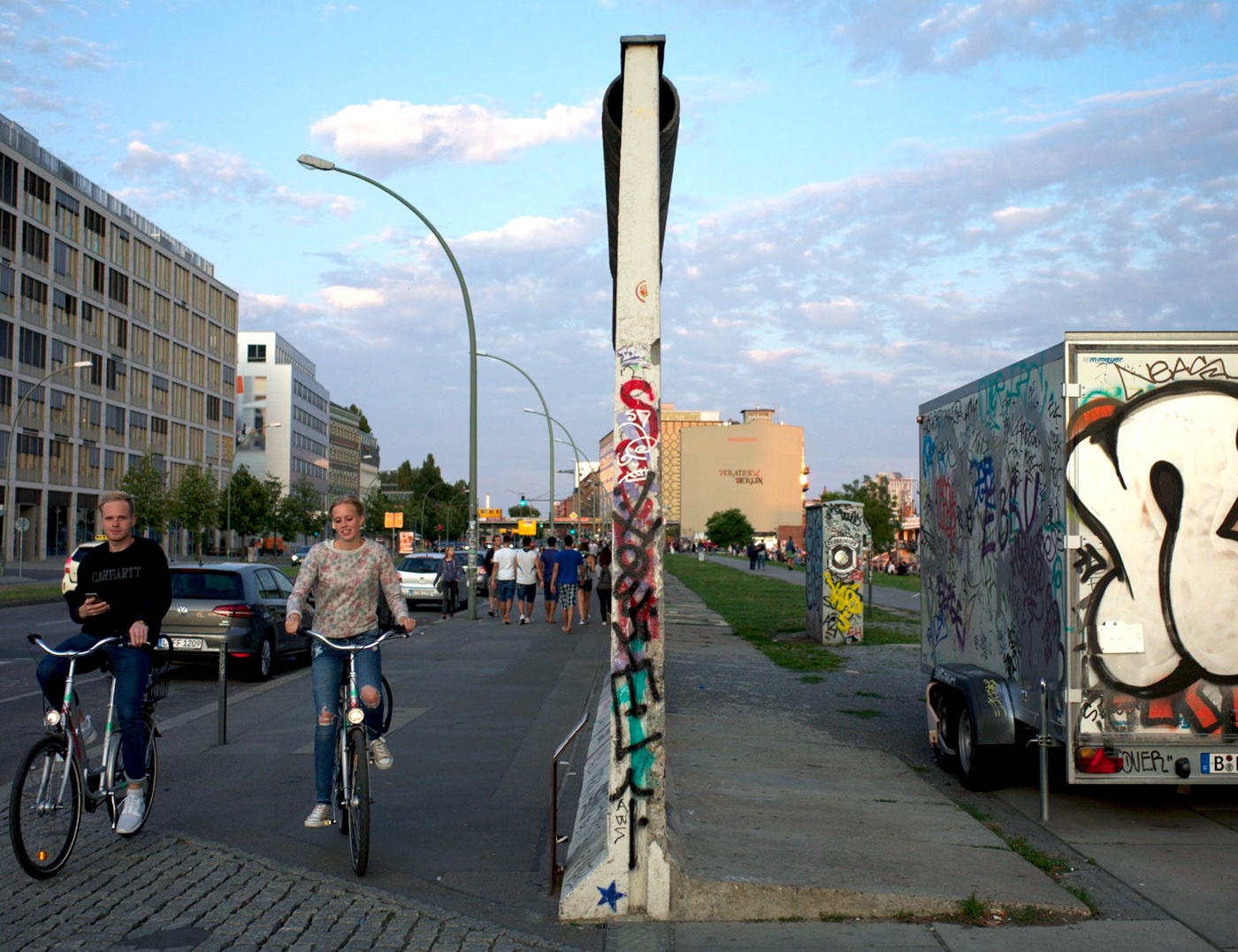 a couple riding bicycle on the Berlin wall.
