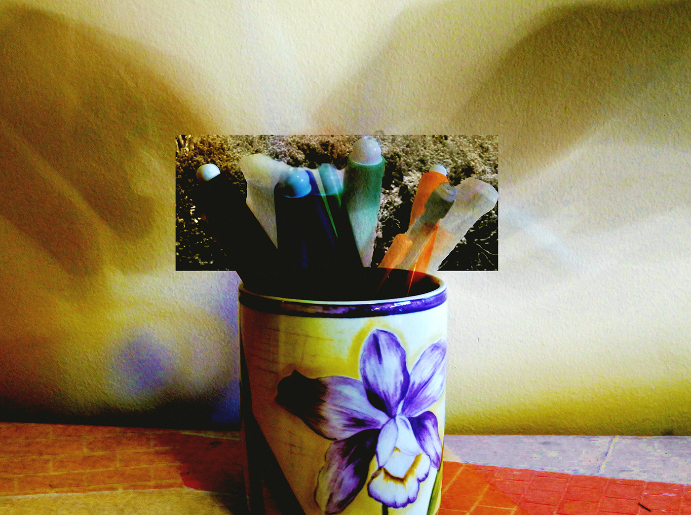 a mug filled with markers and shadow of a hands reaching down