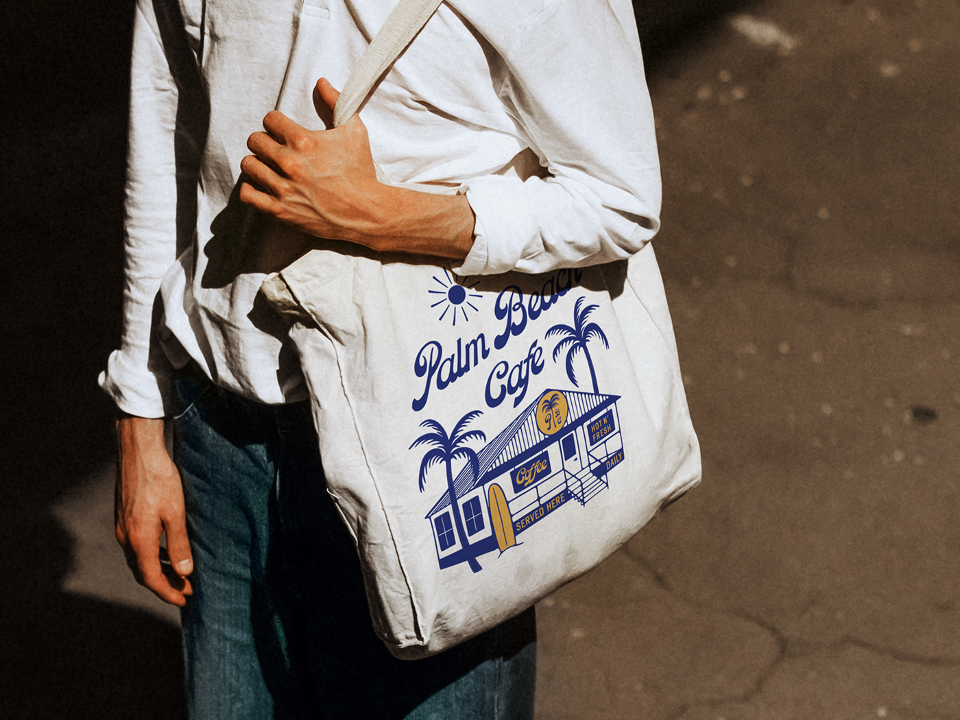 Image of a man wearing a cafe branded tote bag
