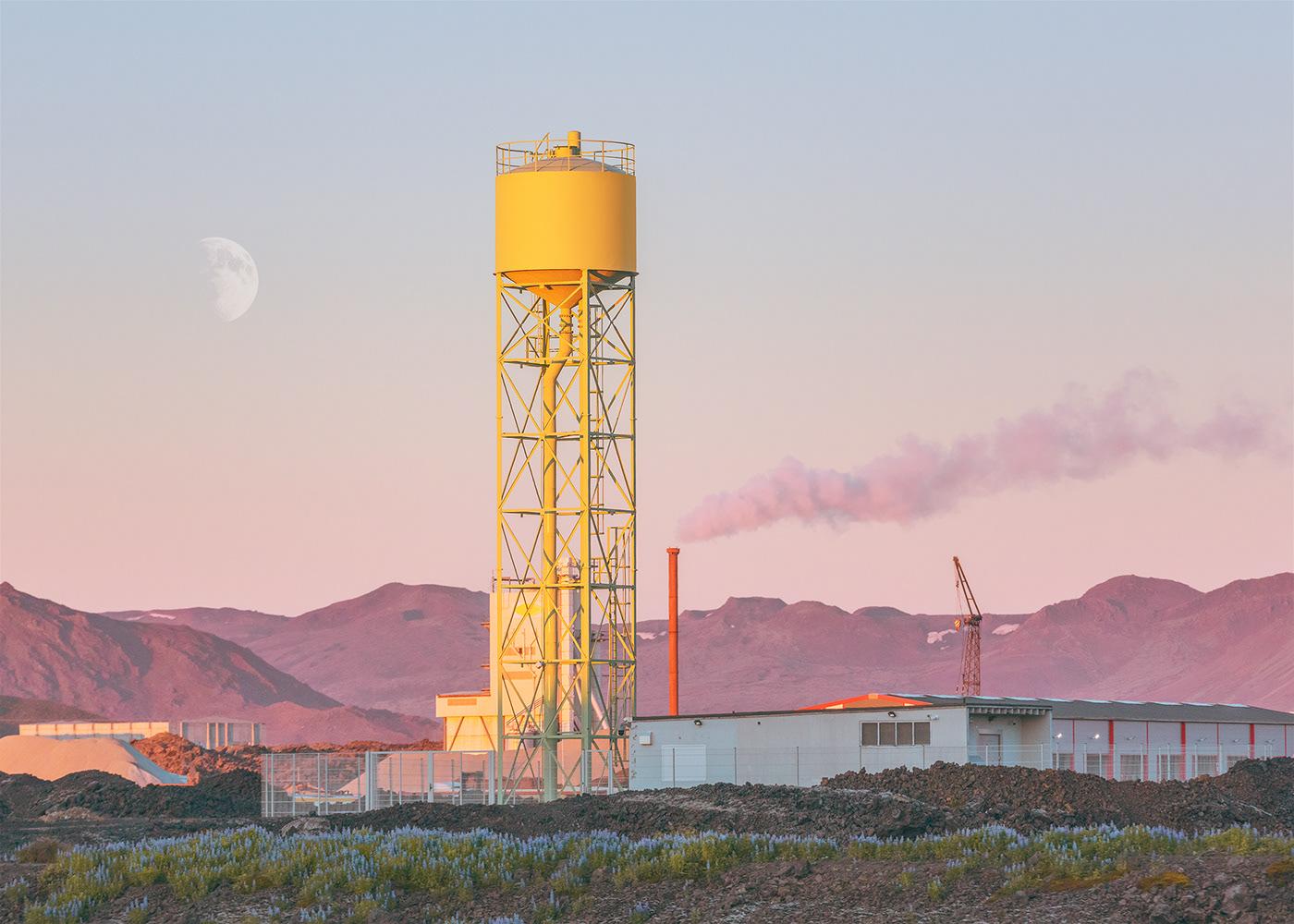 Industrial complex beneath the moon during sunset in Iceland.