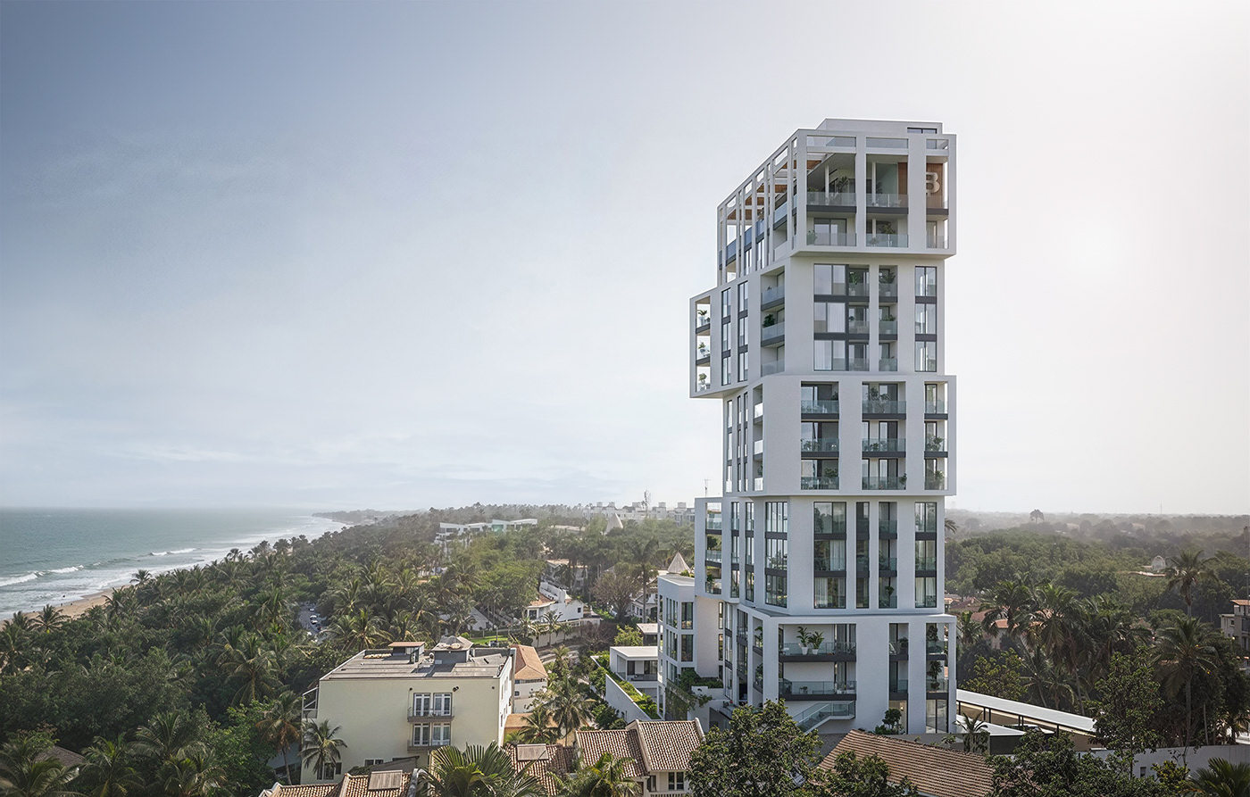 Modern, multi-storey residential building on a coastal landscape with a broad view of a beach