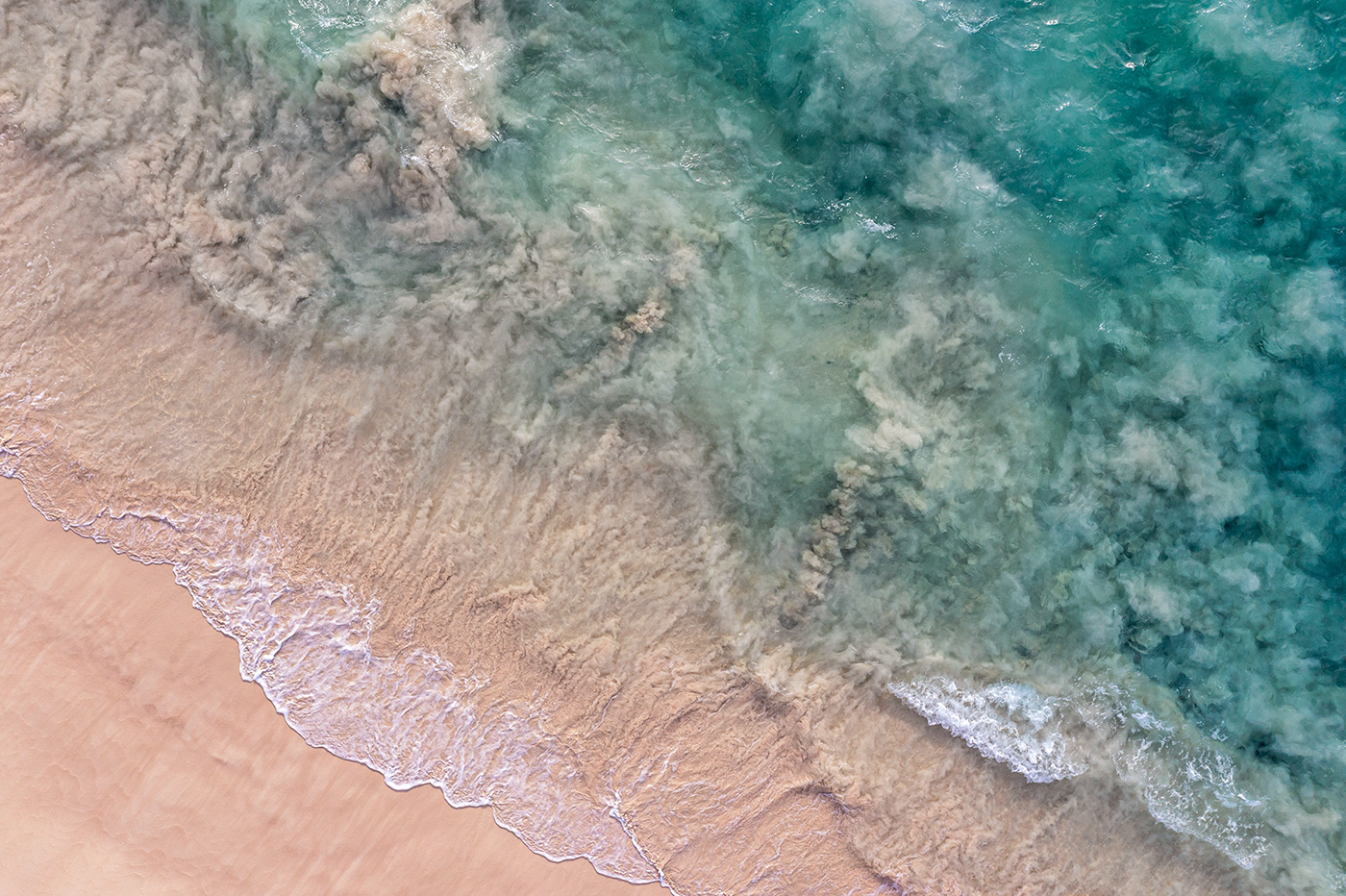 Aerial view of waves sweeping against the sandy beach of Makalawena on the Big Island of Hawaii.