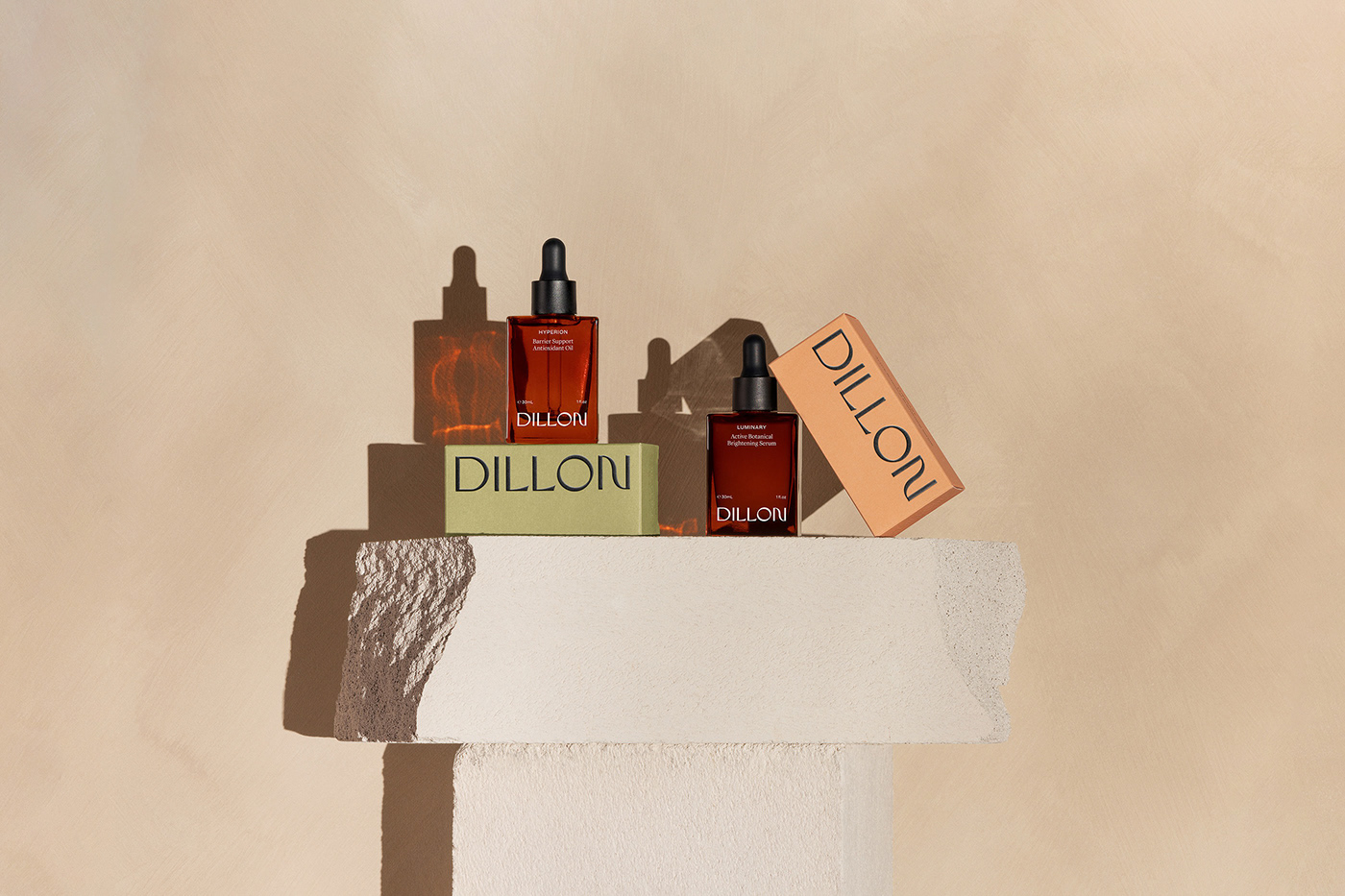 Two product boxes by Dillon skincare sit with two beauty products on a cream brick