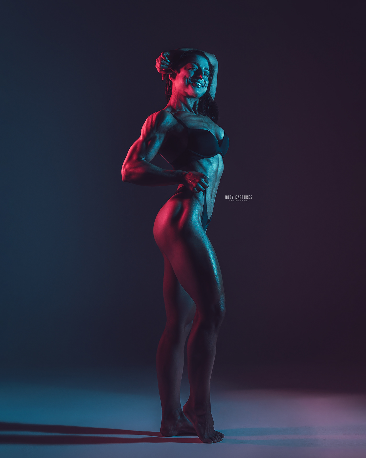 athletic muscular women posing in a photostudio with red and cyan lights