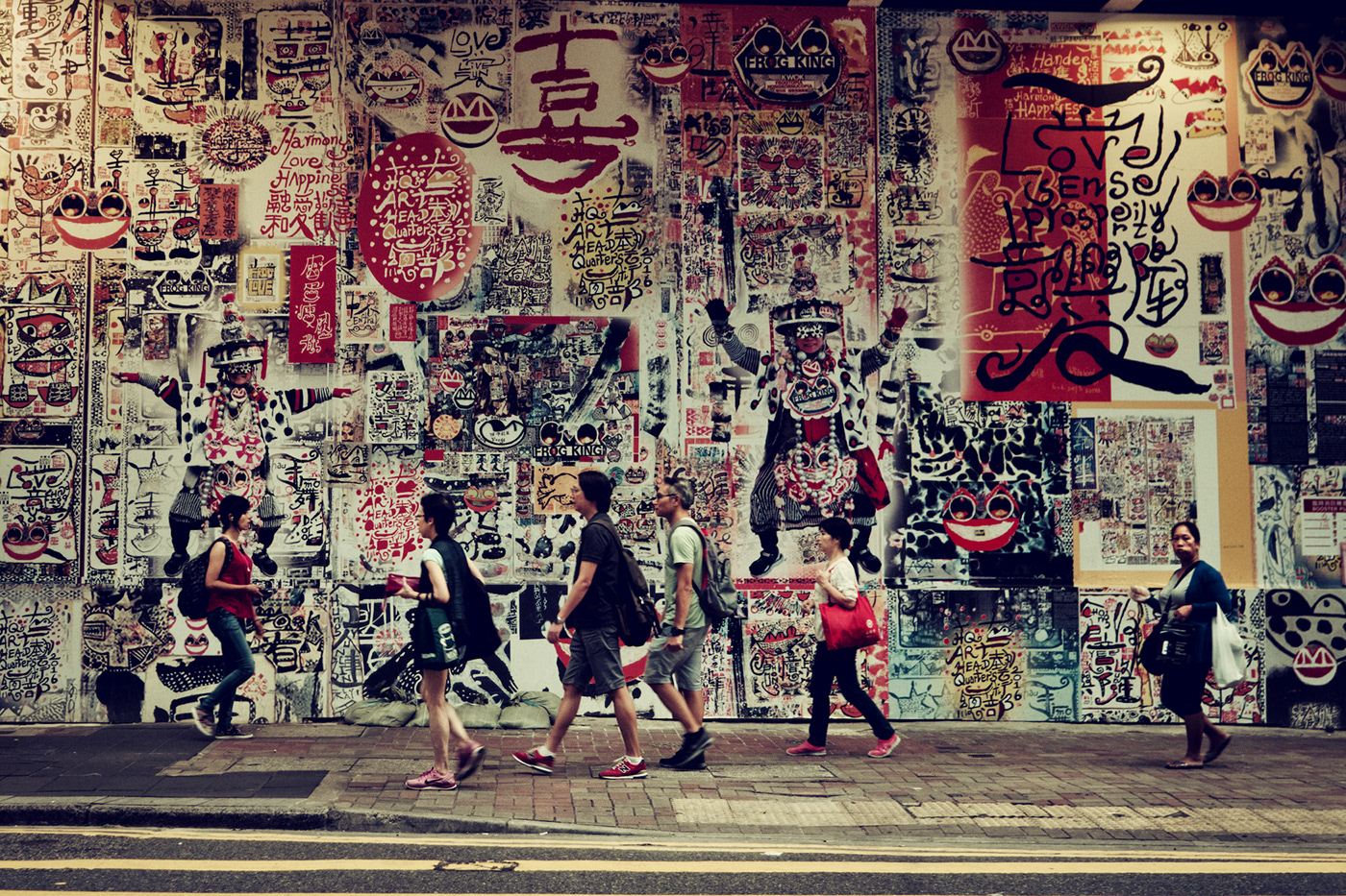 People walking in front of a wall covered by art. Hong Kong
