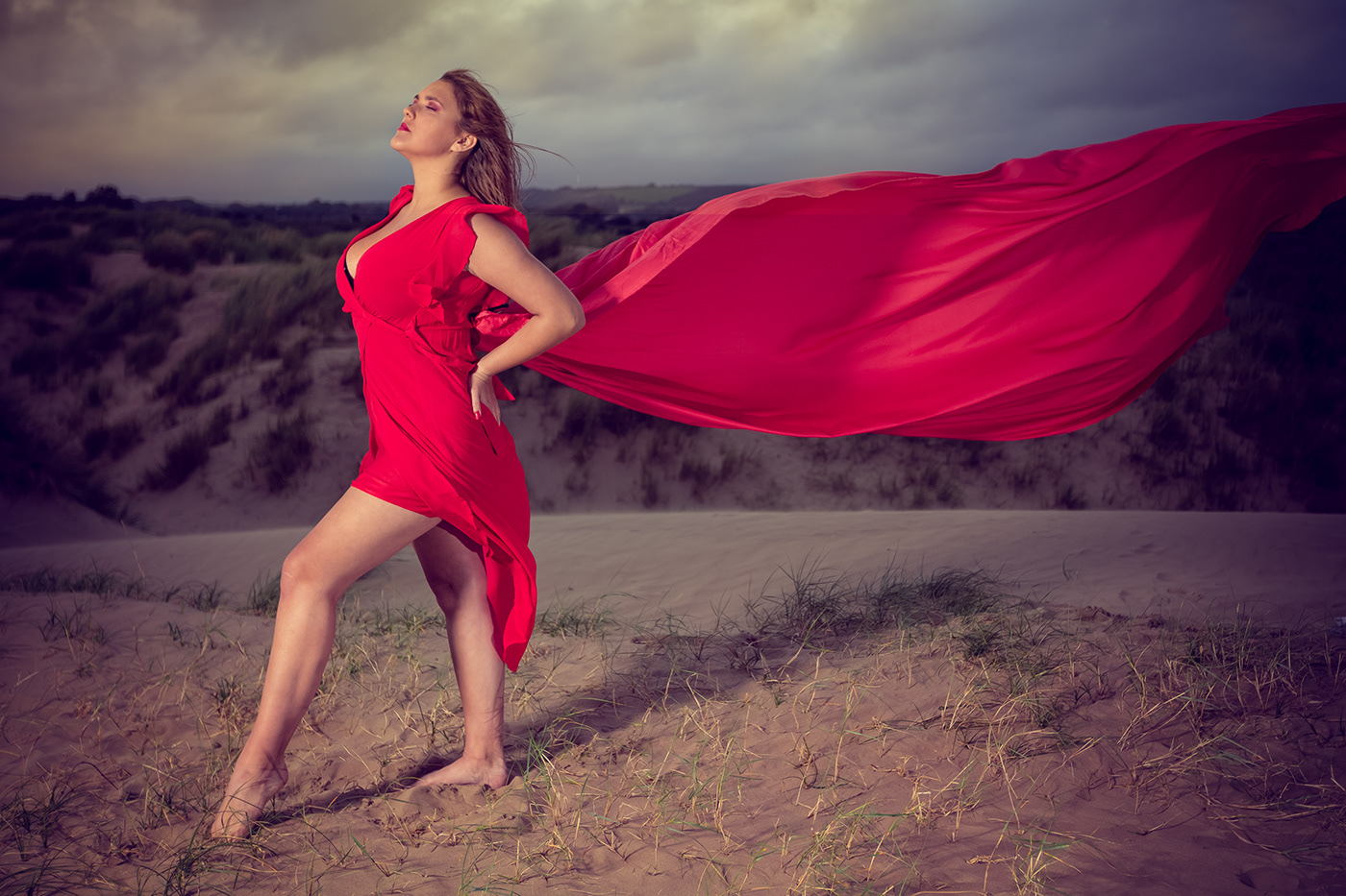An all red fashion model photo shoot  with a dress blowing in the wind