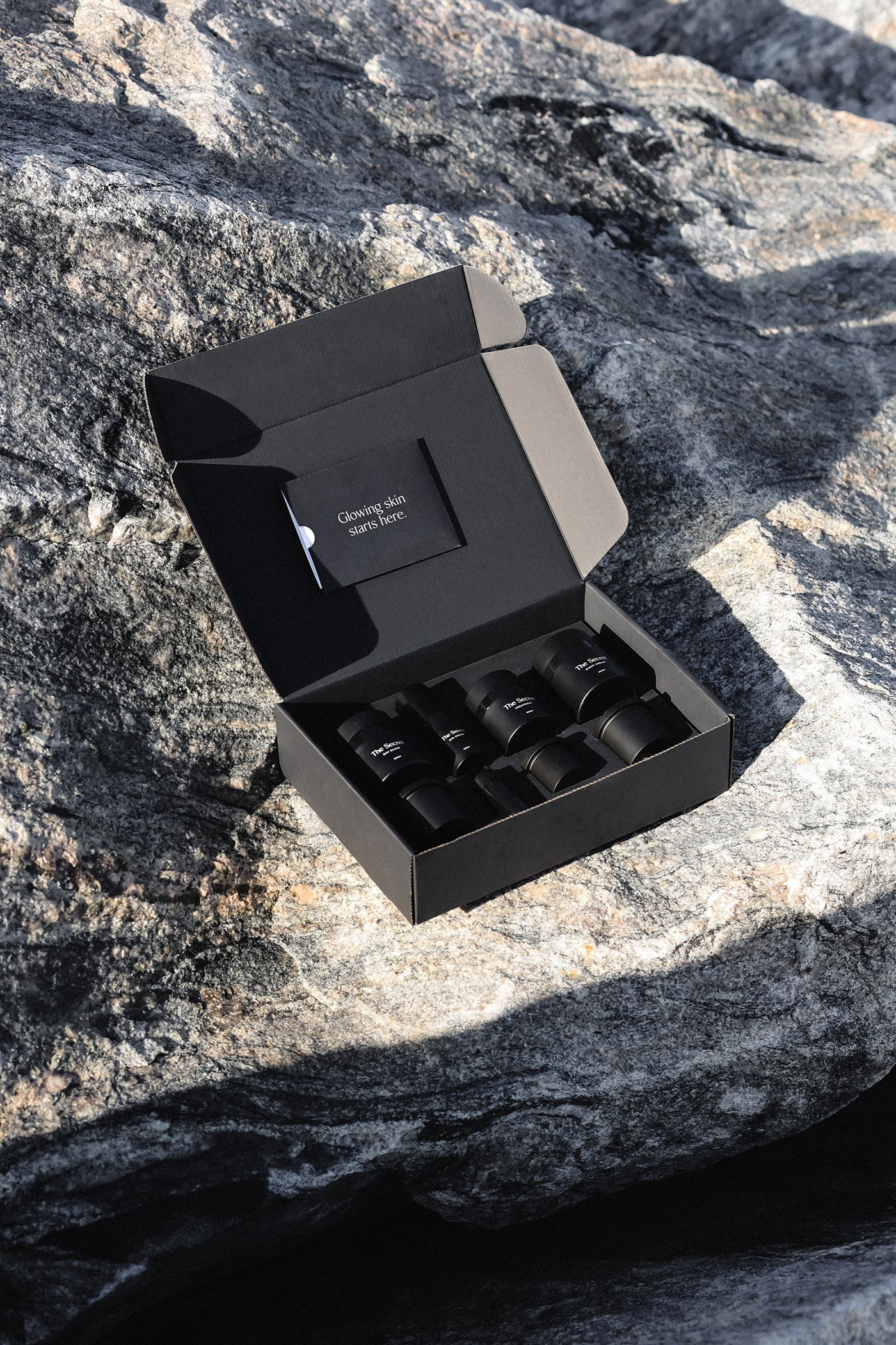 Open black ecom mailer box sits with products inside it on the rocks