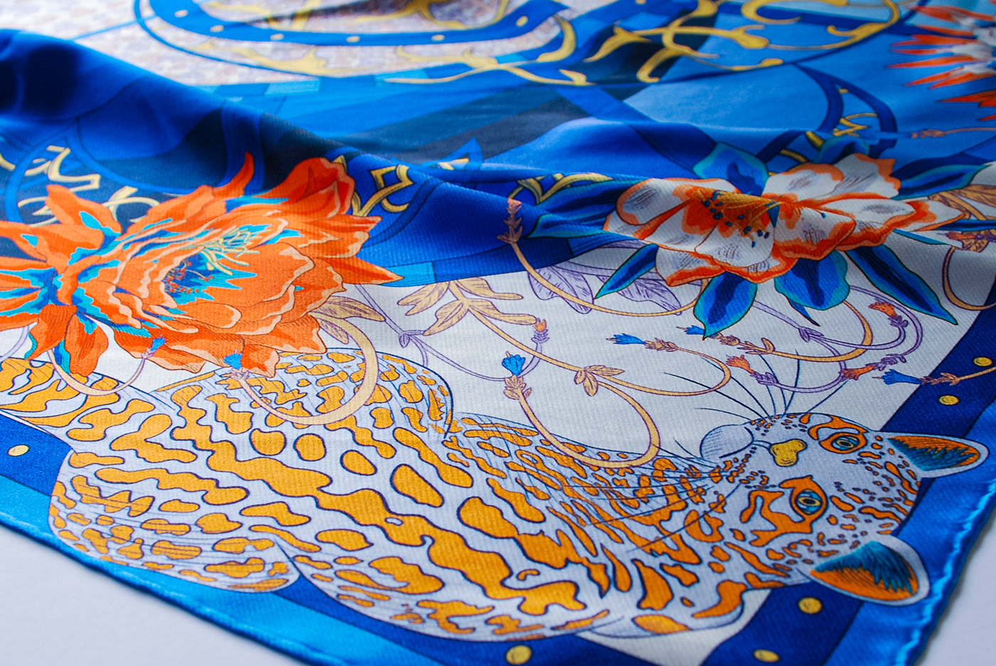 Photograph of a blue silk scarf depicting an ocelot and flowers.