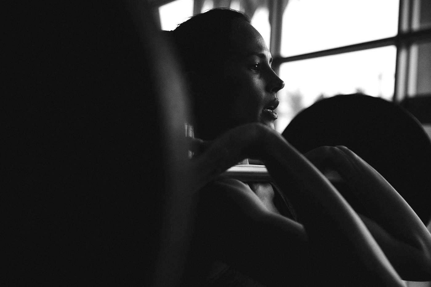 Woman concentrating and focussing on lifting weights in a fitness studio. Black and white photograph