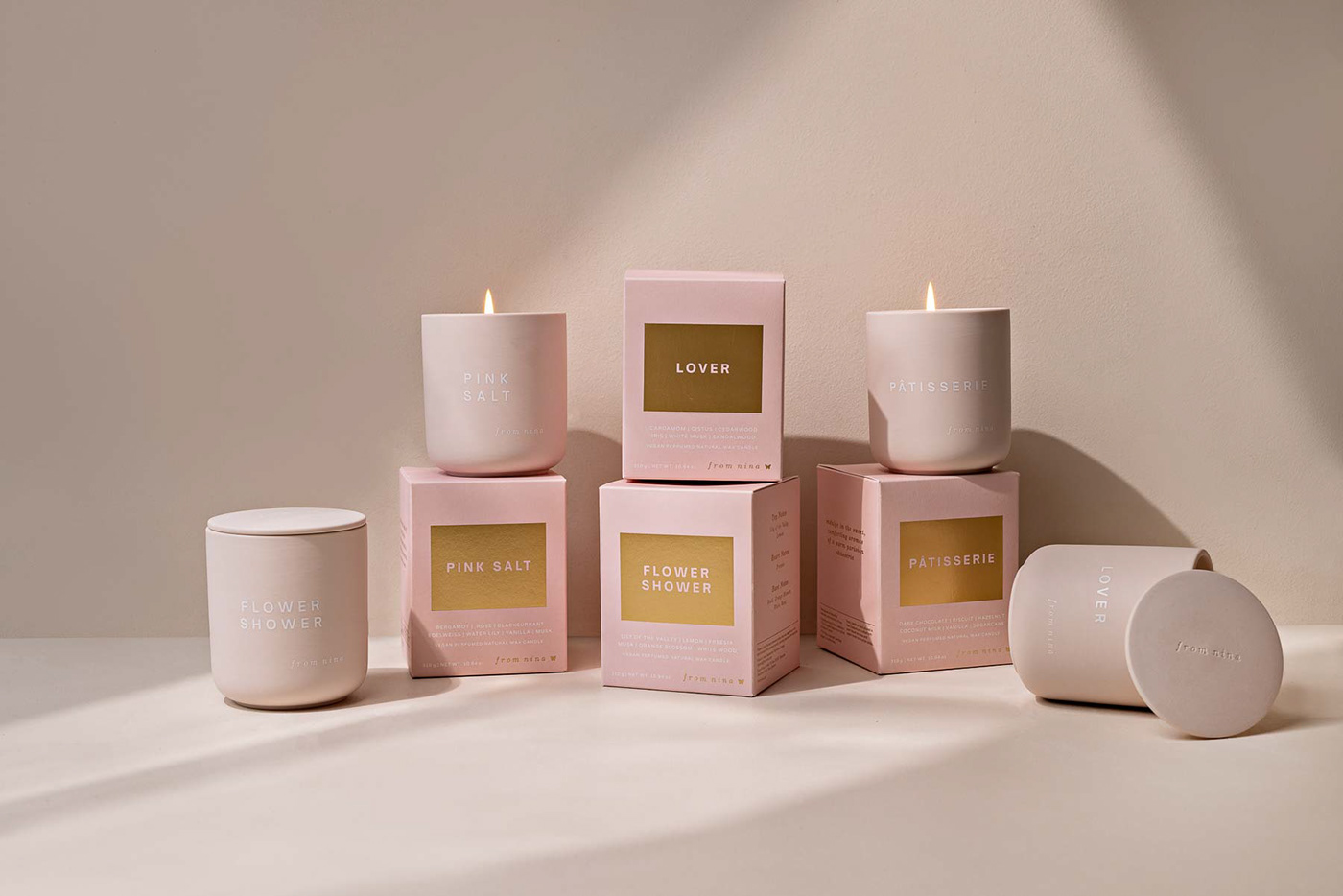 4 candle boxes and their ceramic candles sit in a neutral pink setting