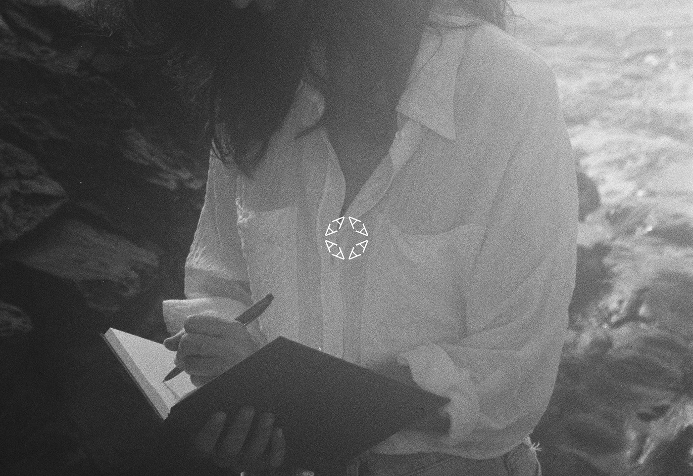 Photography of writer Ana Haro holding a notebook with her logo.