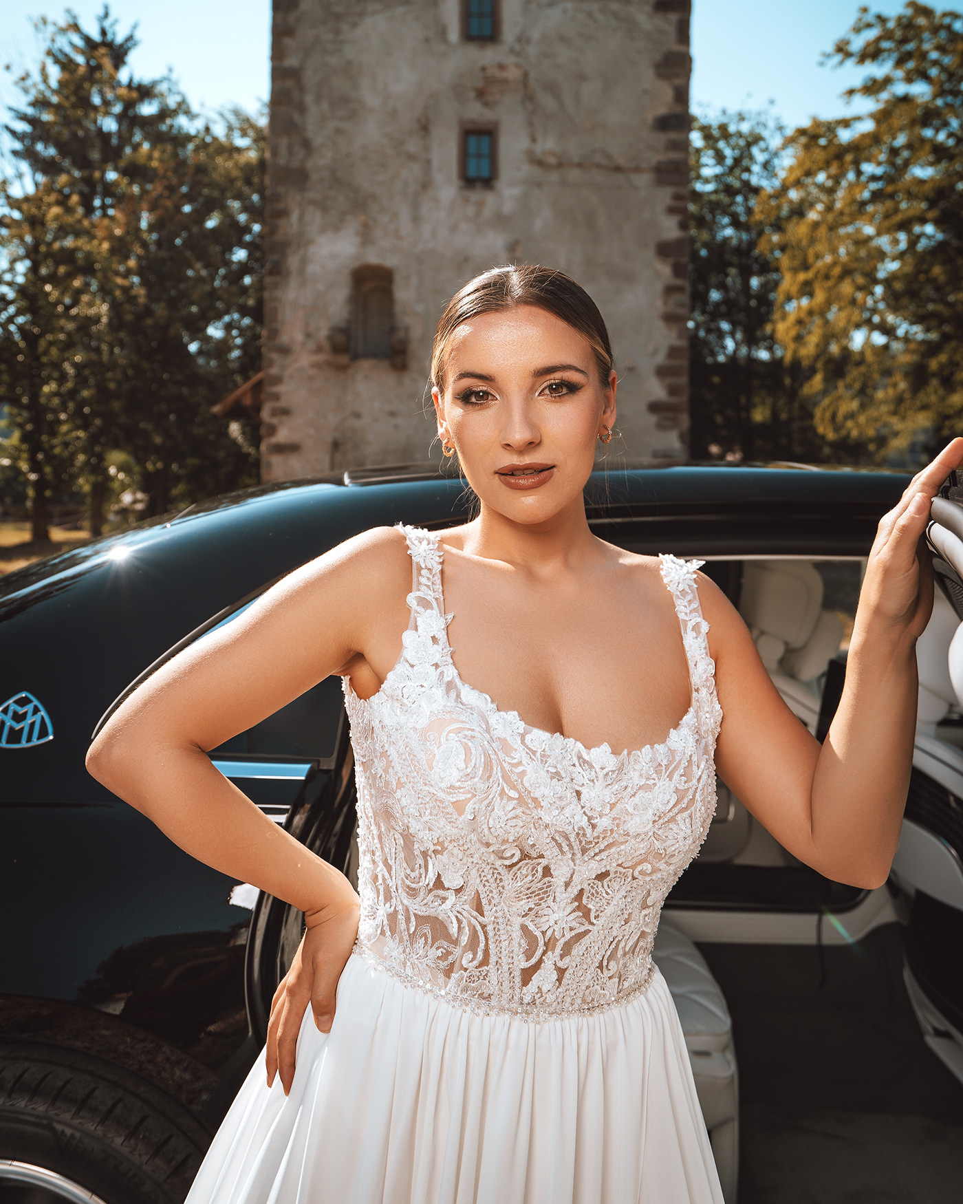 bride standing in front of a car, holding its door
