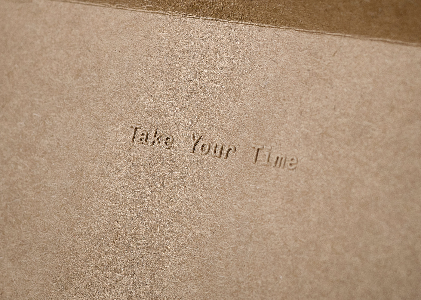 Closeup of blind embossed message on a kraft envelope by Baina towels