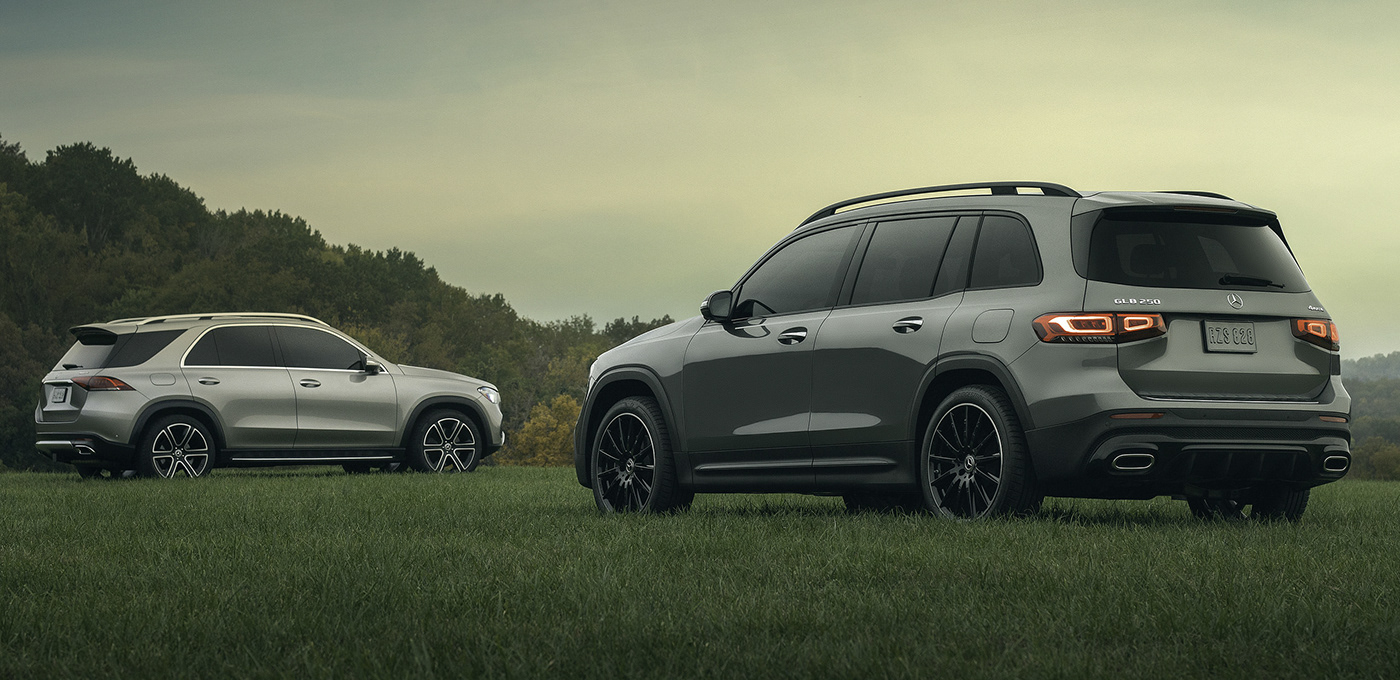 Two Mercedes-Benz SUVs on a grassy hill during sunset