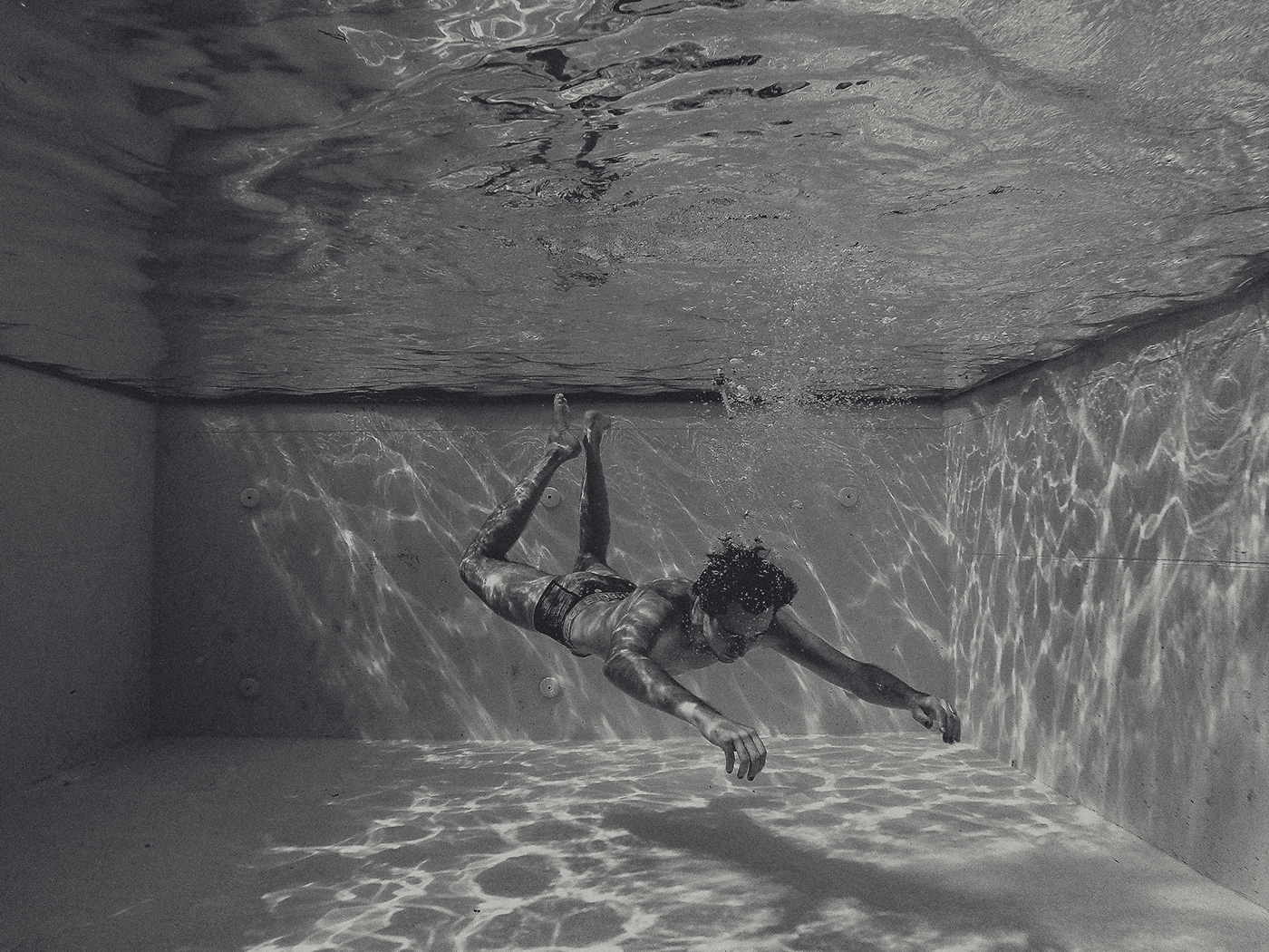 Image contains: male body in underwear, floating in pool, underwater shot
