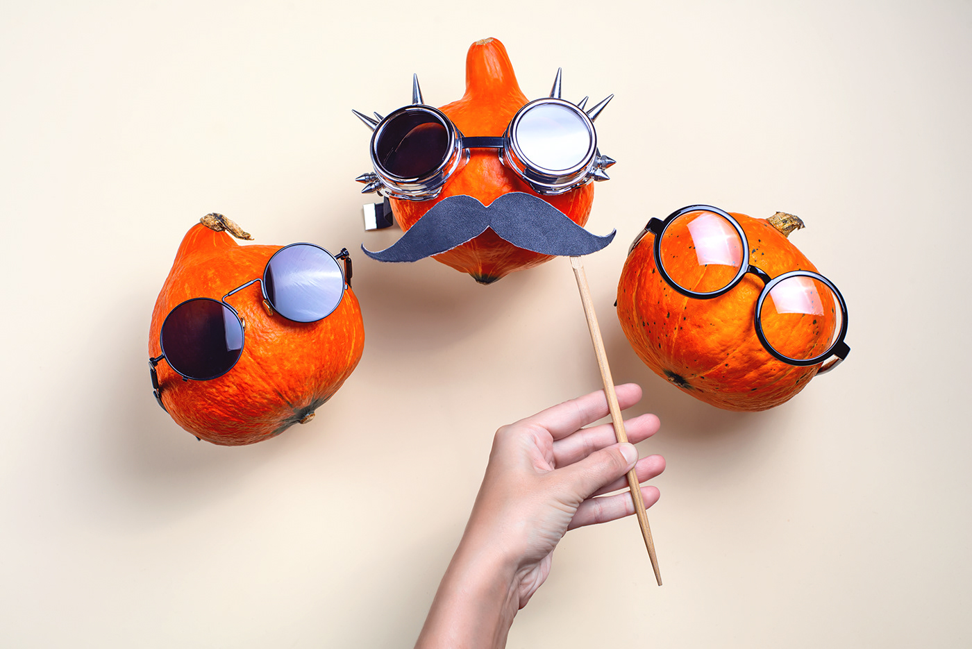 Three orange rocker pumpkins with glasses and a mustache on a light background. Halloween concept.