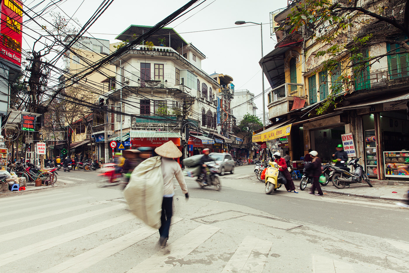 Vietnamese man carries a big bag across the busy road in the Old Quarter, Hanoi, Vietnam