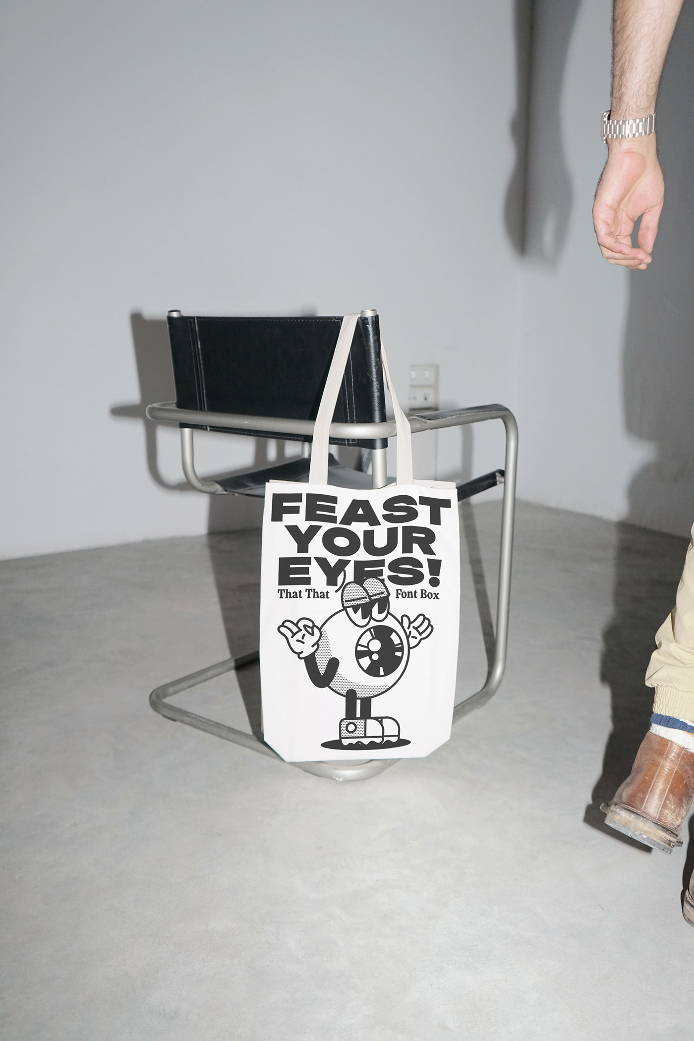 tote bag hanging on a chair. the bag has a graphic of a cartoon eyeball with eyeballs on it. 