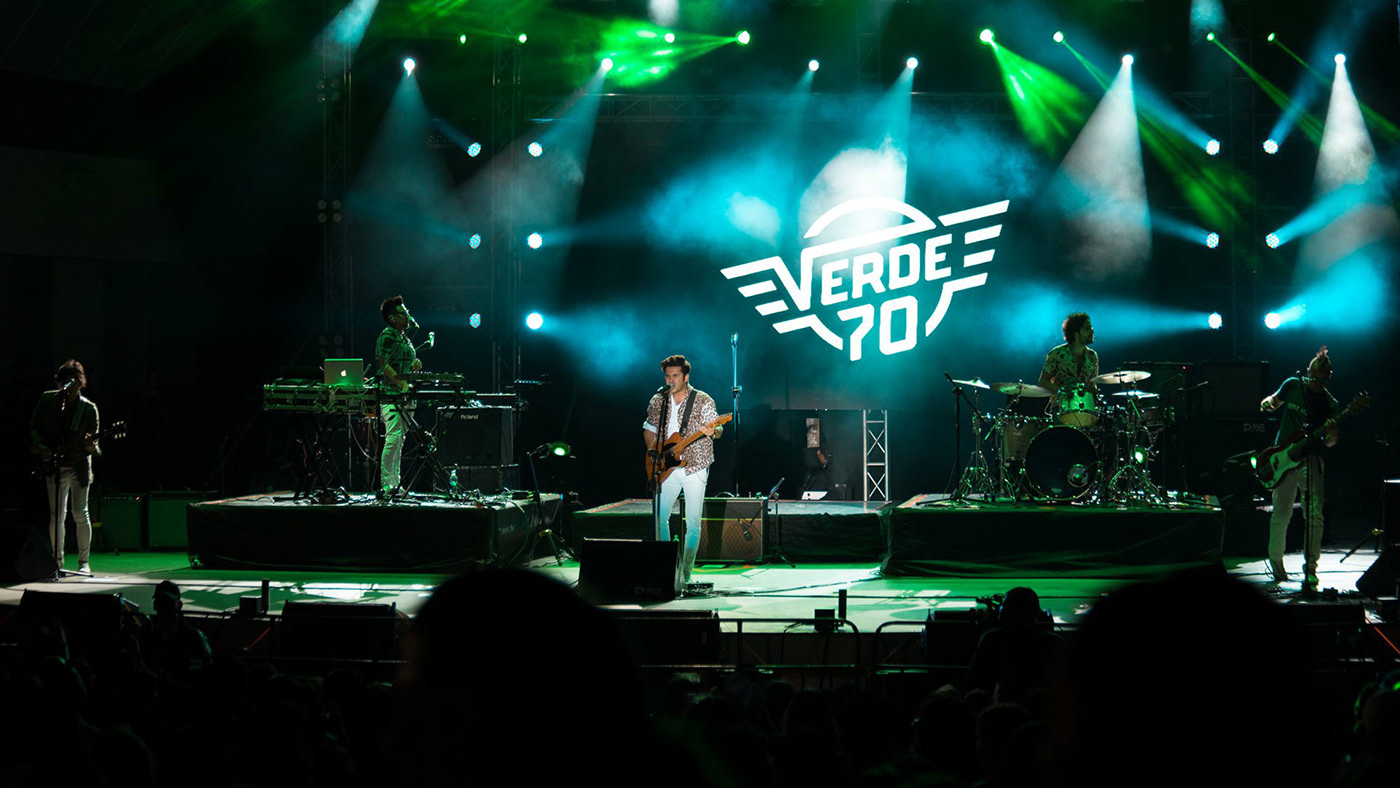 Verde 70 playing in a concert with their logo projected in a background screen