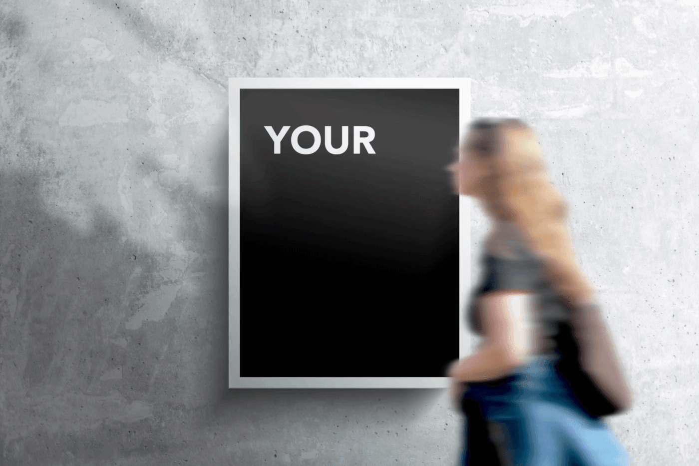 Free .PSD Framed poster mockup, fully customisable on a concrete wall with a woman passing by.