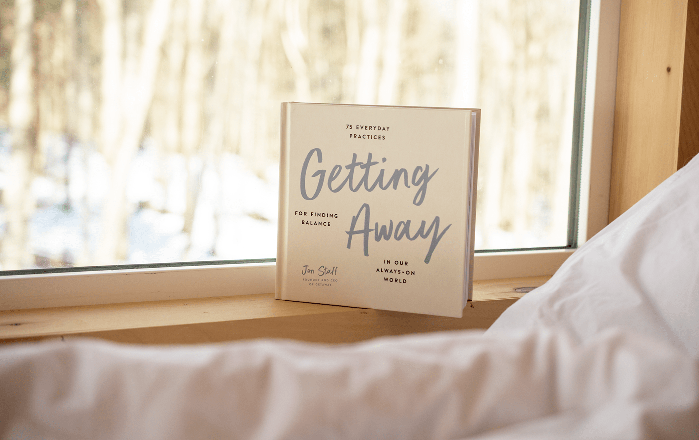 Photo of the Getting Away book sitting on the window sill of a Getaway cabin (in the winter). 