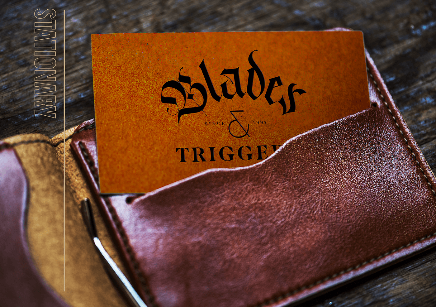 Business card reading “Blades & Trigger” in a leather wallet with “STATIONARY” above.