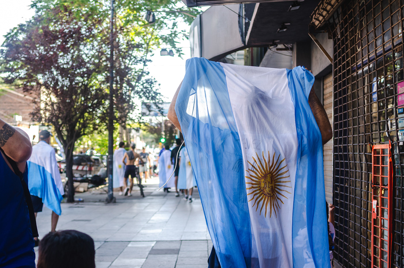 Un hombre sostiene con orgullo la bandera argentina mientras camina hacia los festejos del mundial.
