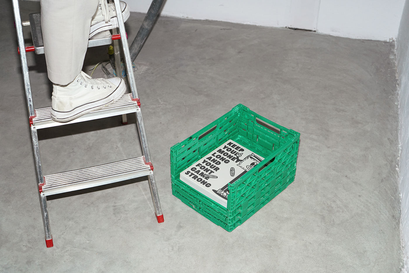 a magazine in a green crate on the floor by a ladder
