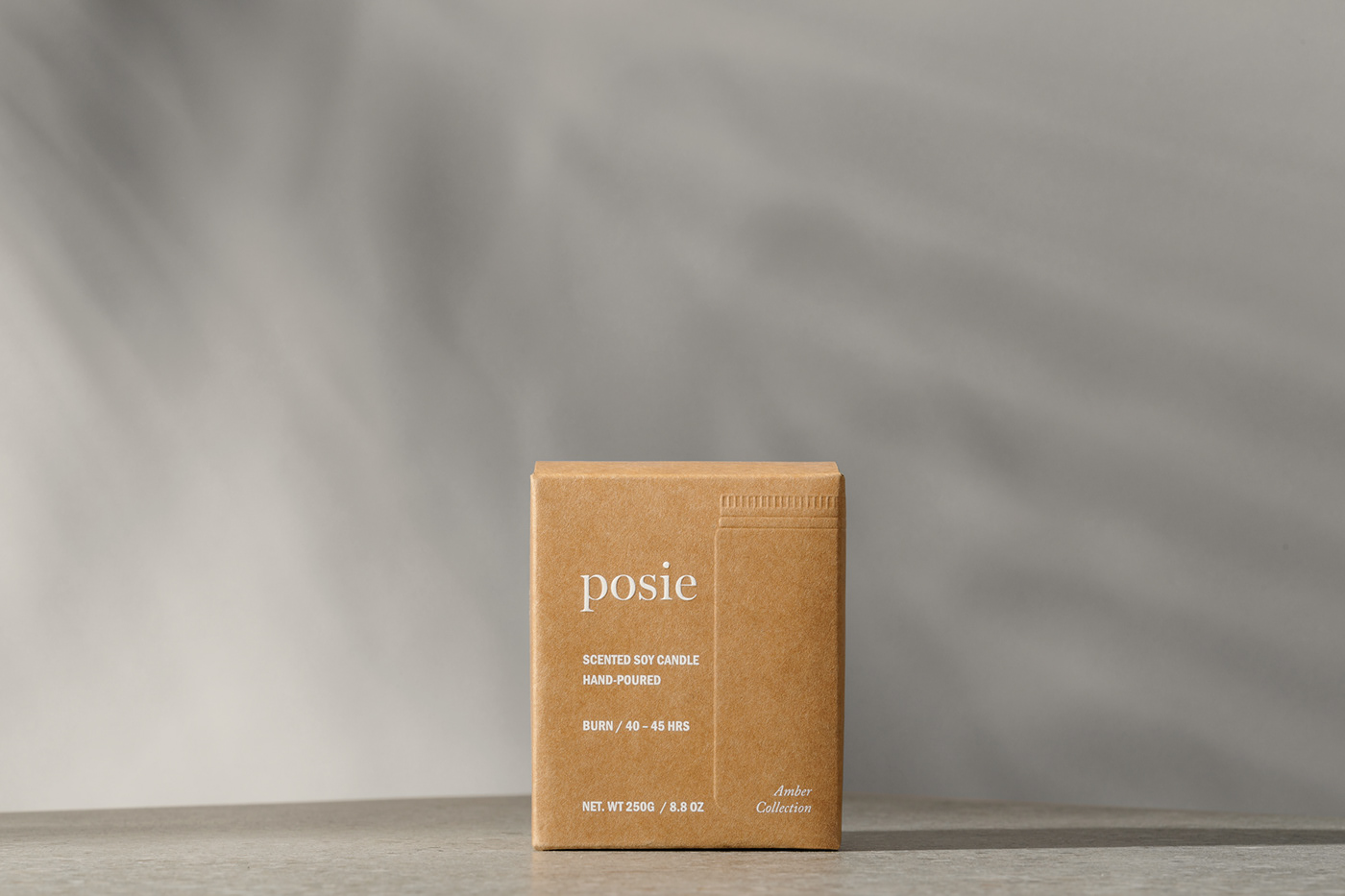 Posie soy candle kraft box sits in a naturally-lit studio environment