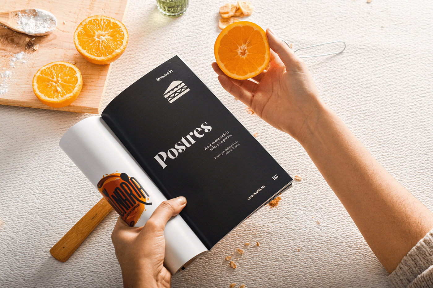 Spread of cookbook and orange in hand.