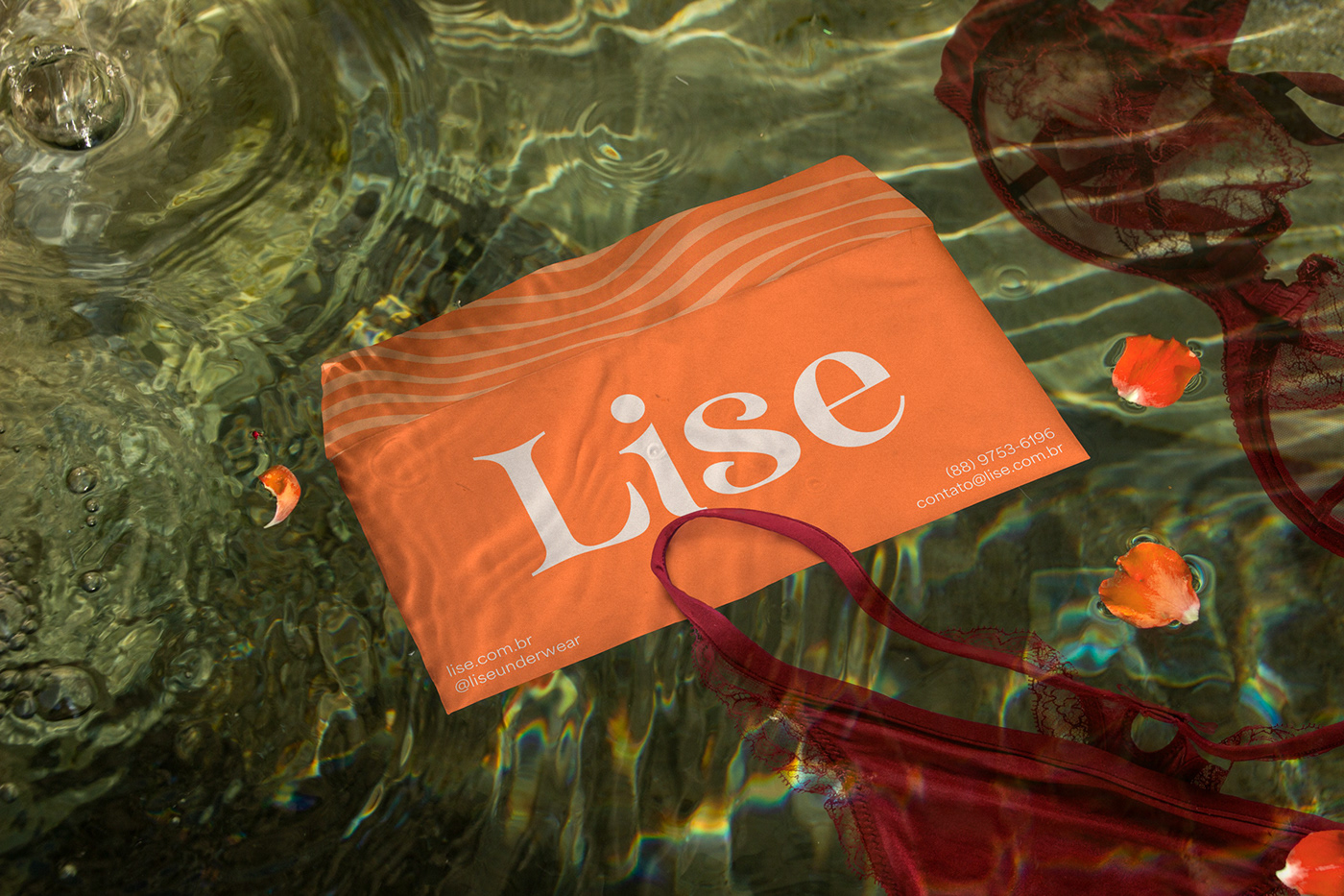 Orange envelope floating in crystal clear water with lingerie next to it.