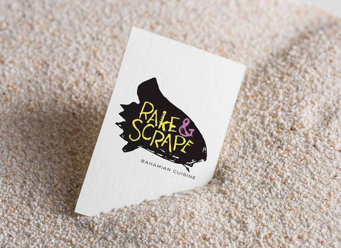 Business card propped up in white sand with restaurant logo printed in center