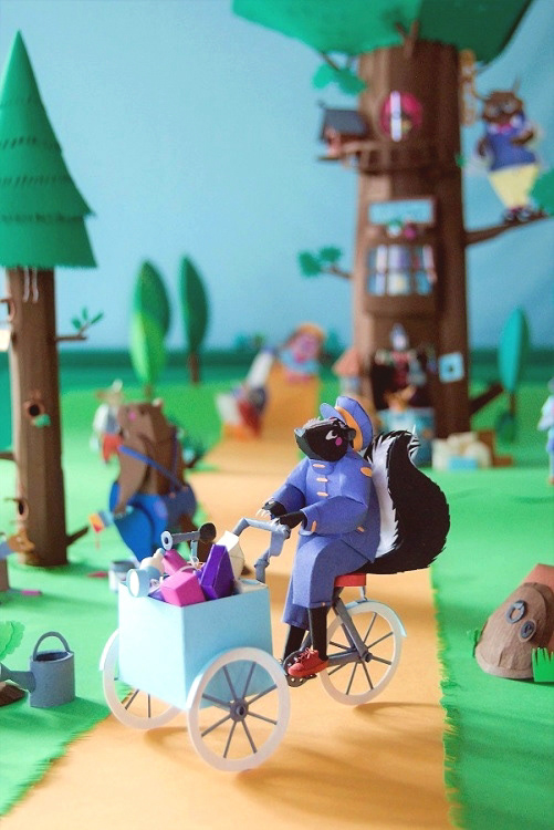 The skunk carrier on his tricycle loaded with packages. In the background, partial view of the woods