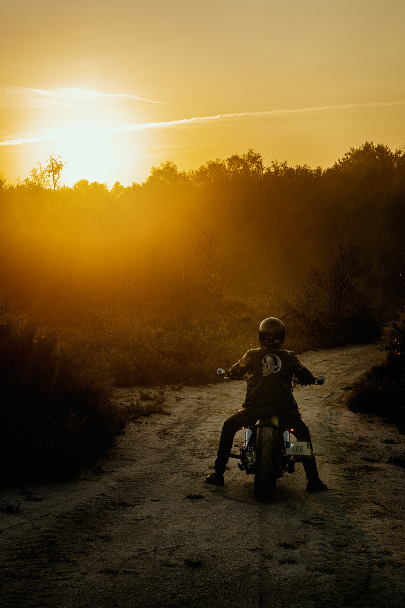 Biker with his bobber by sunset in a western like surrounding
