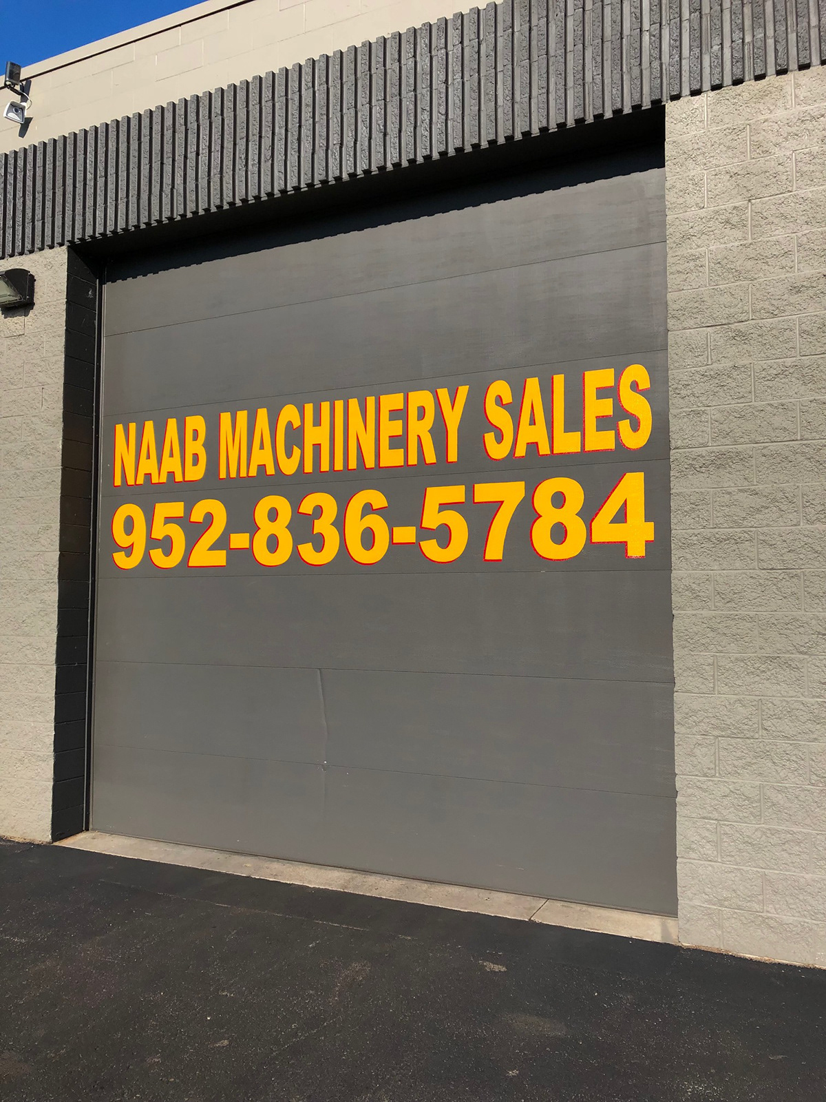 Sign painting on garage doors for Naab Machinery Sales in Blaine, MN.