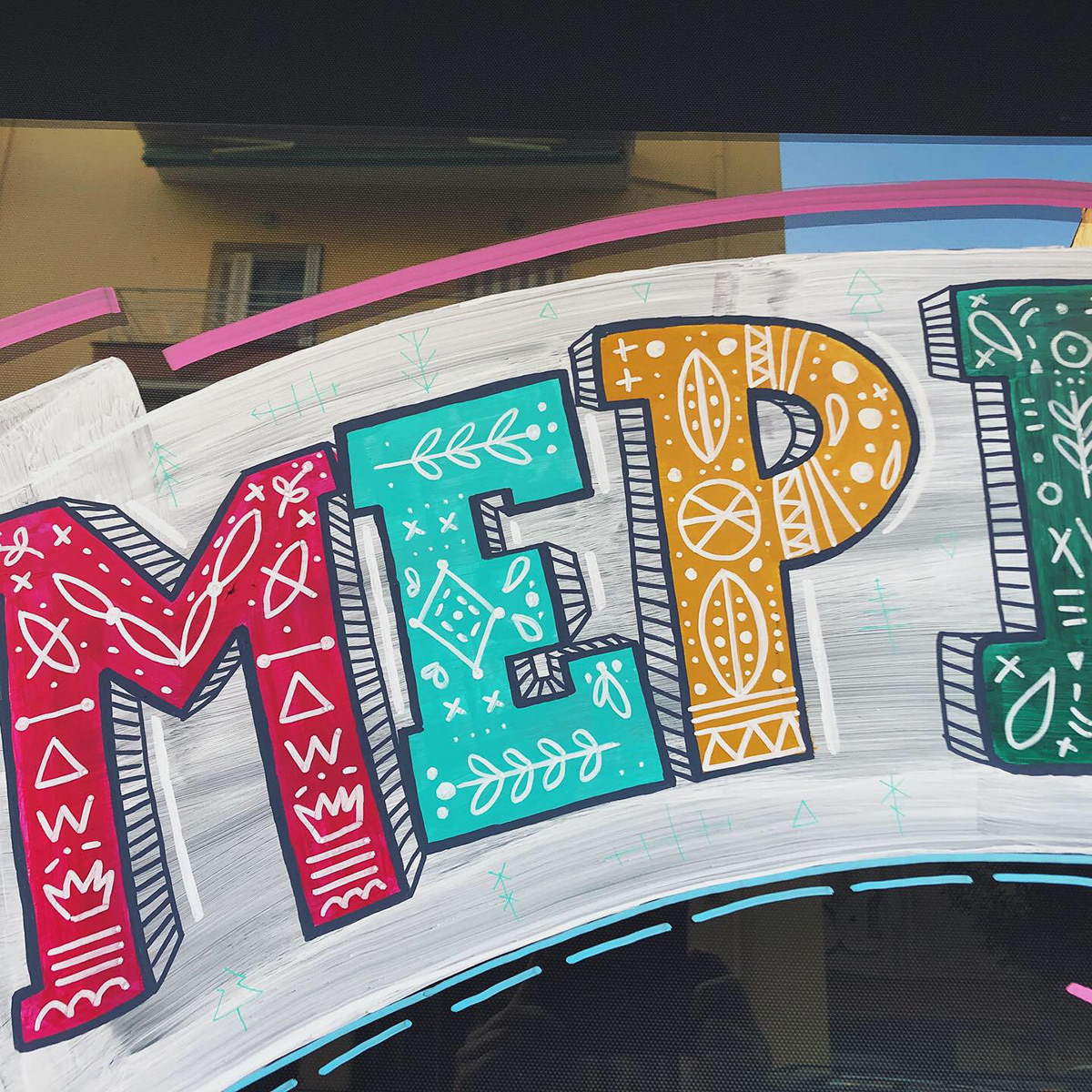 A window display where ''merry xmas'' is handwritten with vivid colours on the glass