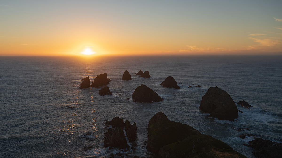 "The Nuggets" rock formations at Nugget Point Lighthouse in New Zealand at sunrise.