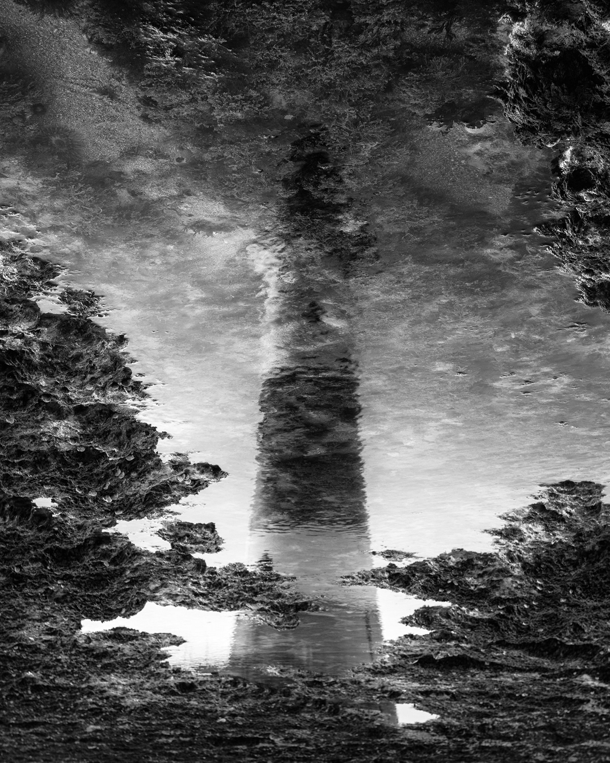 A lighthouse reflected in a rock pool