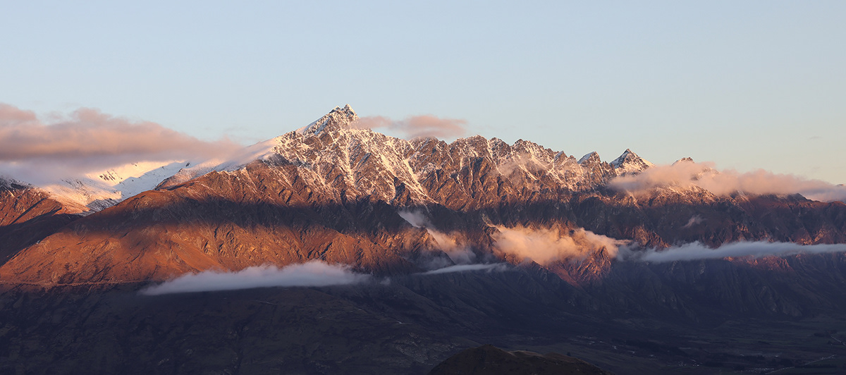 The rugged peaks of The Remarkables mountain range in New Zealand during golden hour.