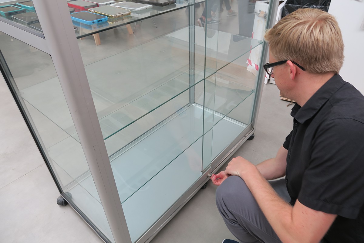 person locking mobile phones in a glass cabinet for a social experiment at falmouth university