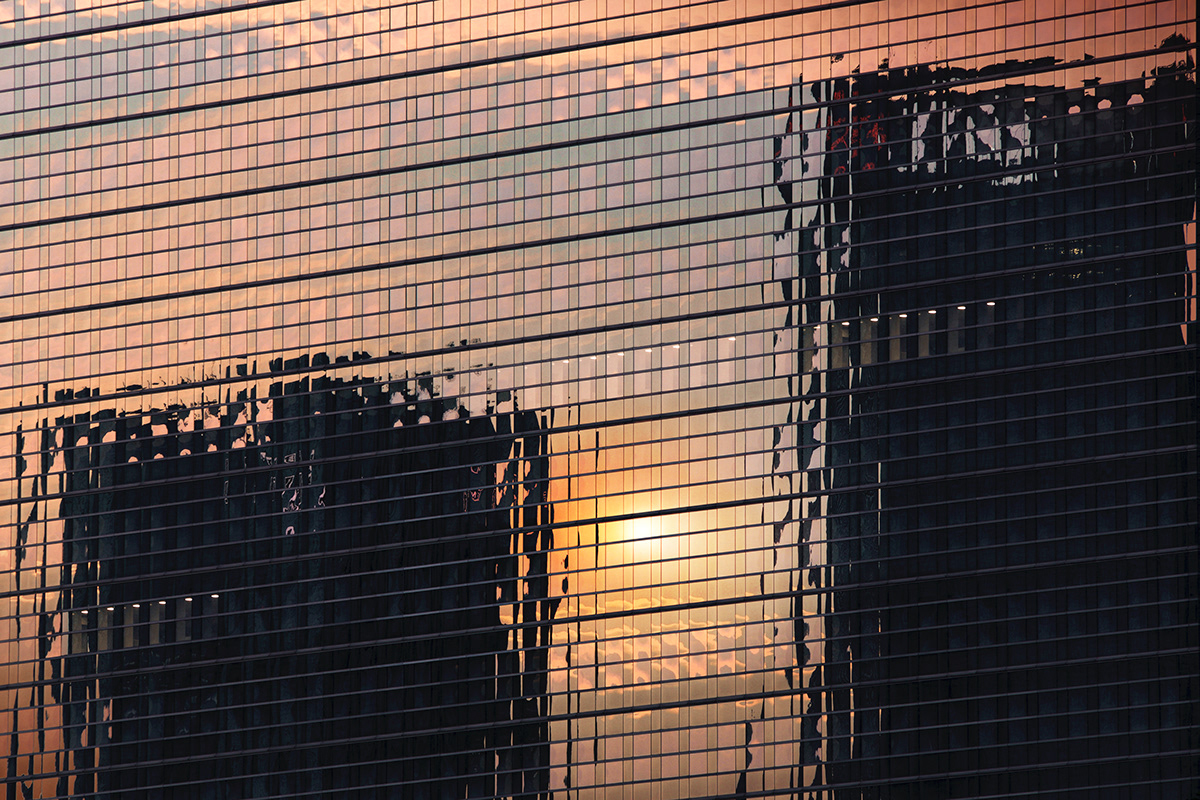 Dramatic sunset refelction on mirroring facade of Pollux Tower at sunrise