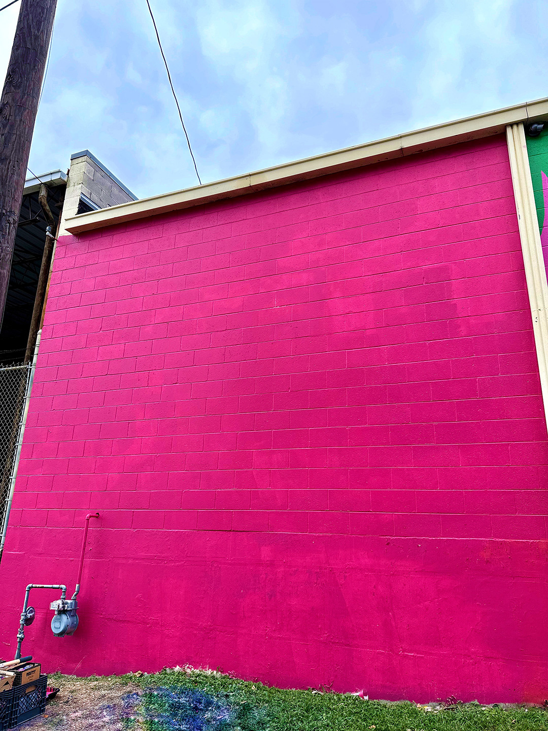 photo of large brick wall painted bright pink for mural