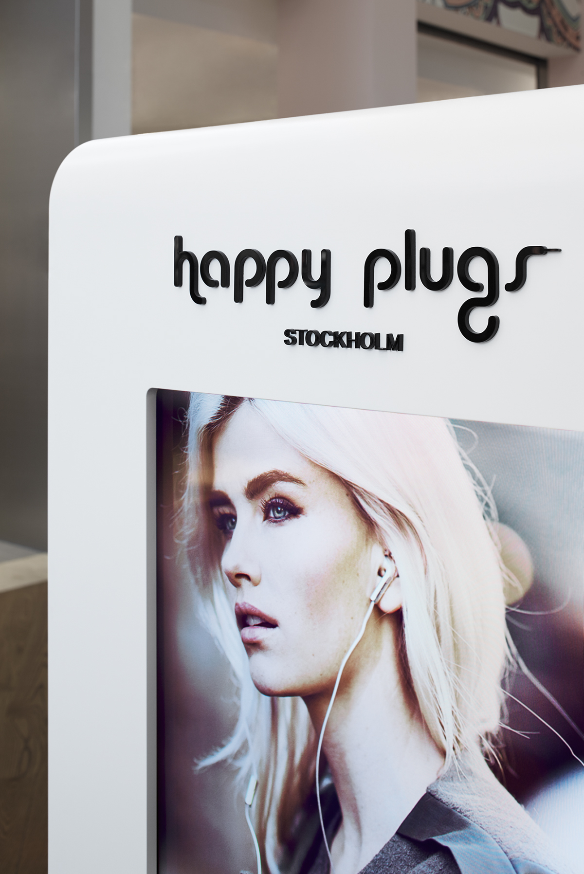 Short side of the Happy Plugs Pop-up Retail Store with digital screens and Happy Plugs Logotype