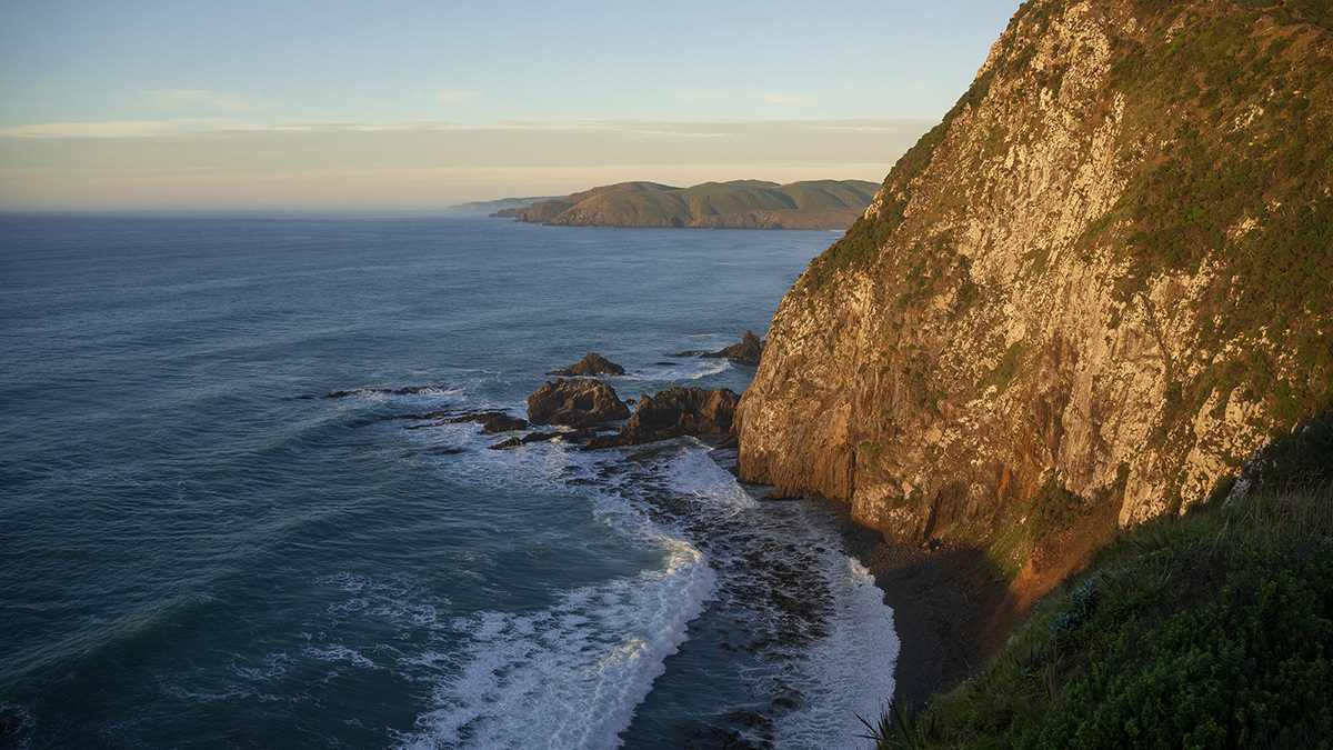 The ocean and nearby cliffs illuminated by the morning sun.