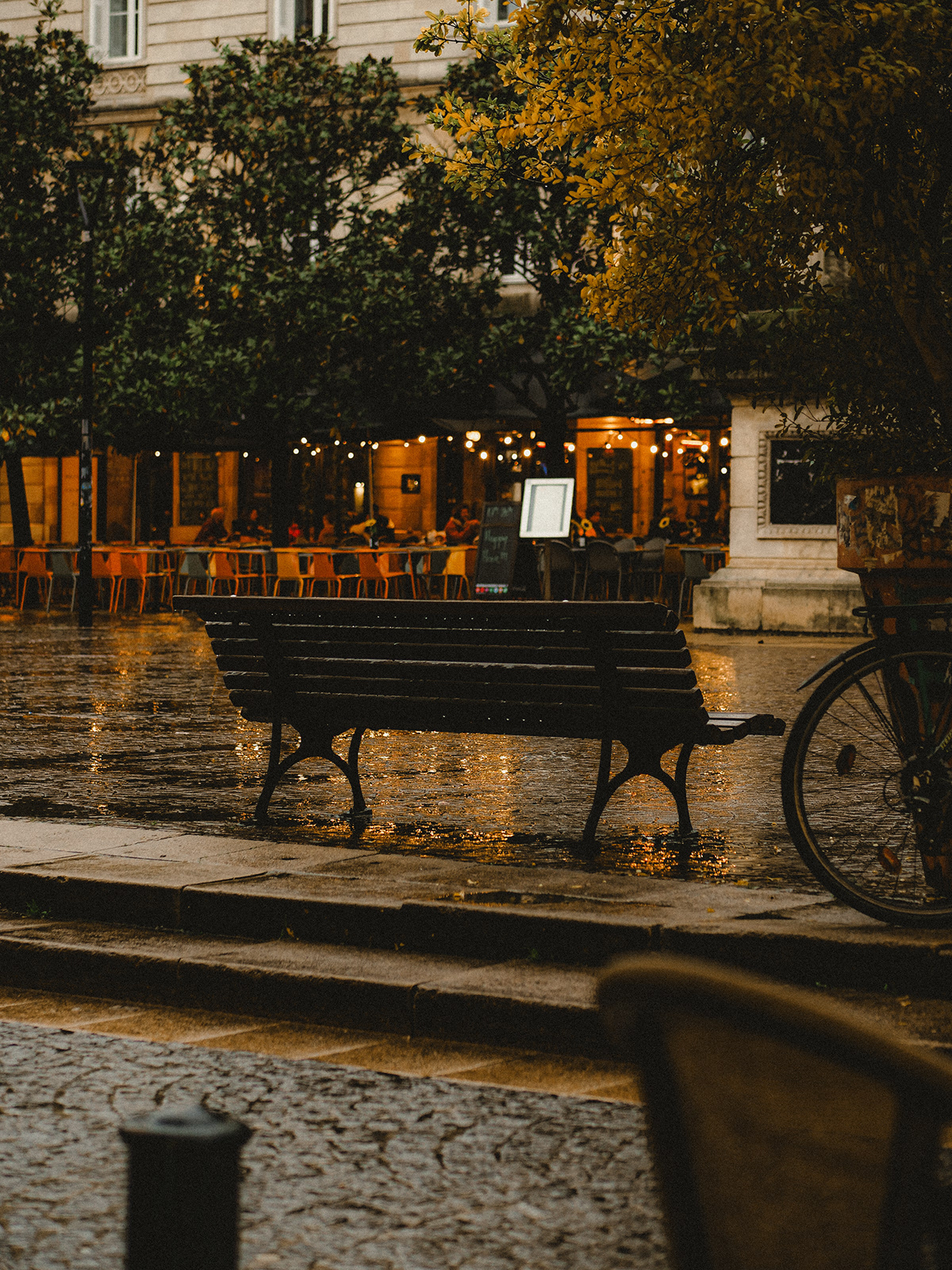 Photographie d'un banc Place Camille Julian à Bordeaux durant une journée pluvieuse. 
