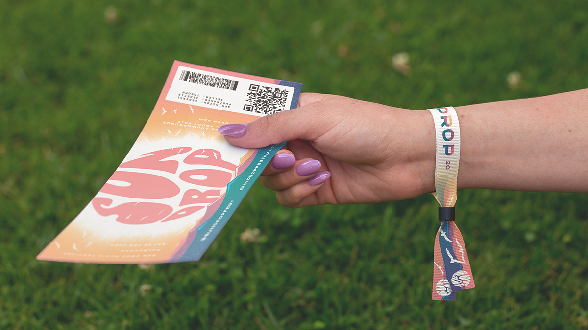 Branded wristband tied around hand holding festival ticket
