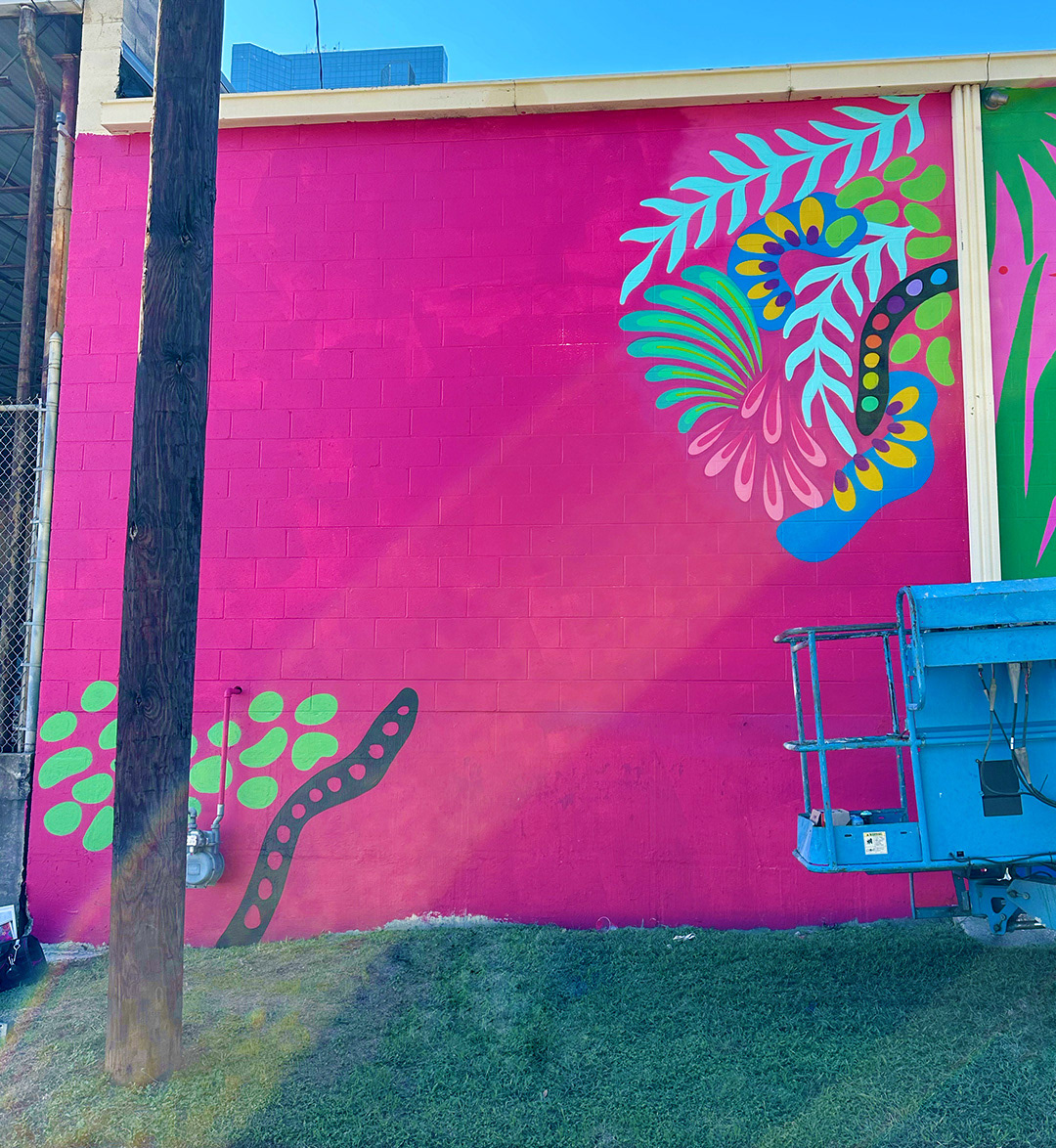 progress photo of mural painting with tropical details on bright pink background