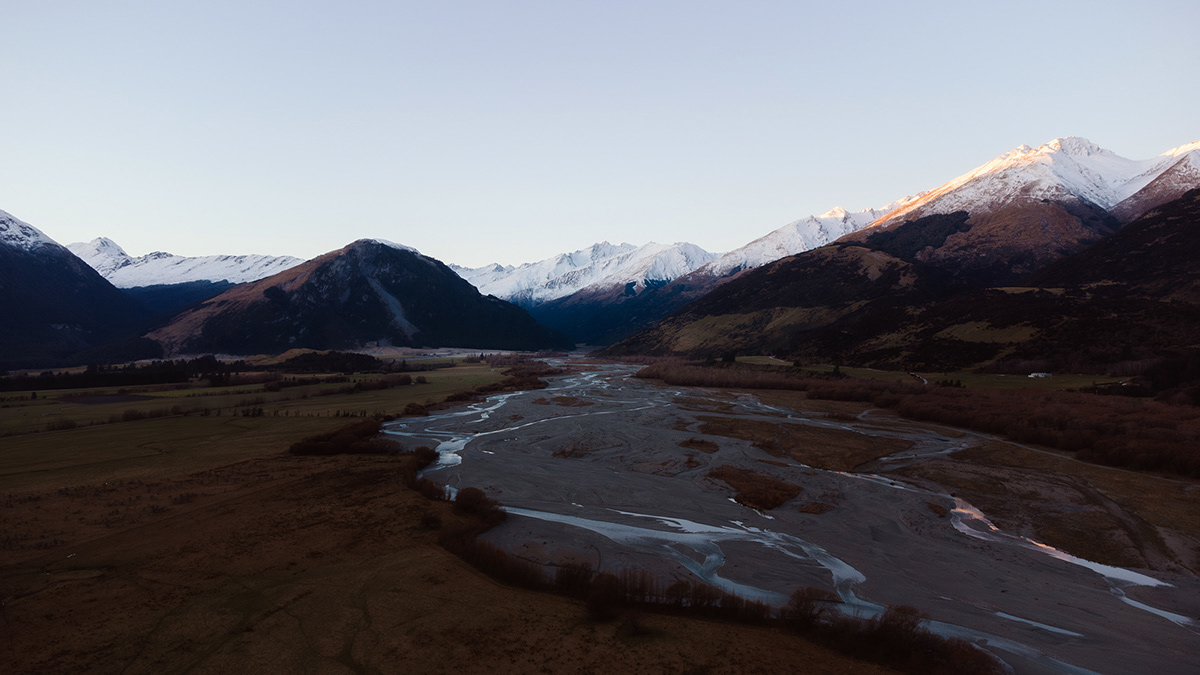 Drone view of river snaking its way out from the snow capped mountains.